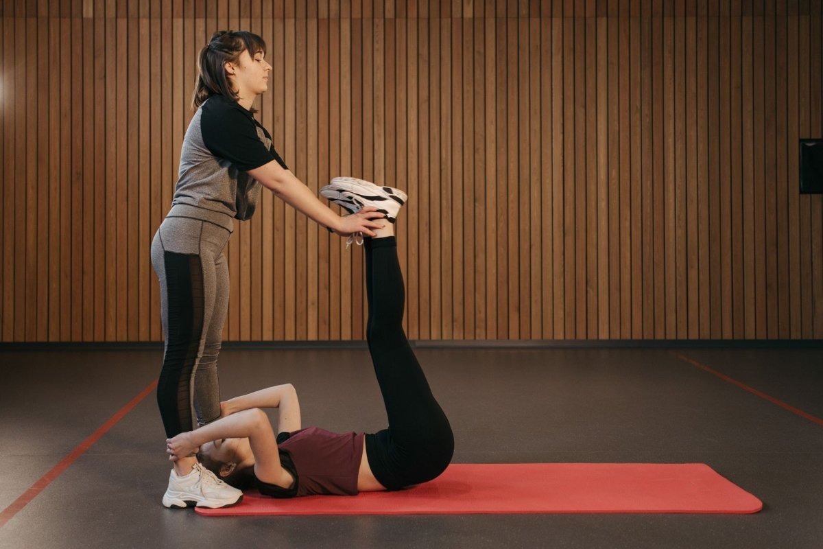 Assisted Stretching Dubai 1 Assisted stretching Dubai — female coach stretching a client's legs on a mat